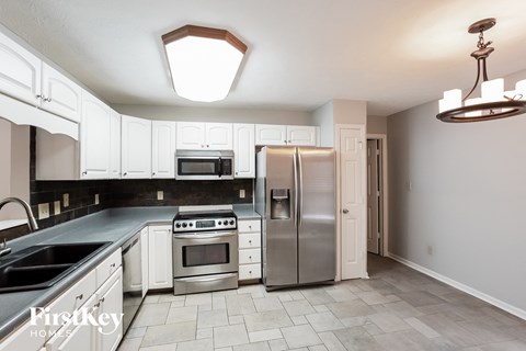A kitchen with white cabinets and a stainless steel refrigerator.