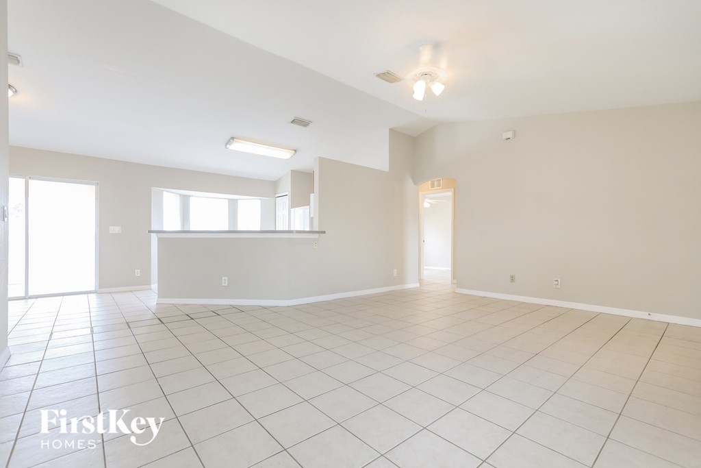 A spacious empty room with a tiled floor and a ceiling fan.