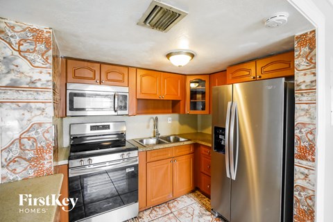 A kitchen with a refrigerator, microwave, oven, and sink.