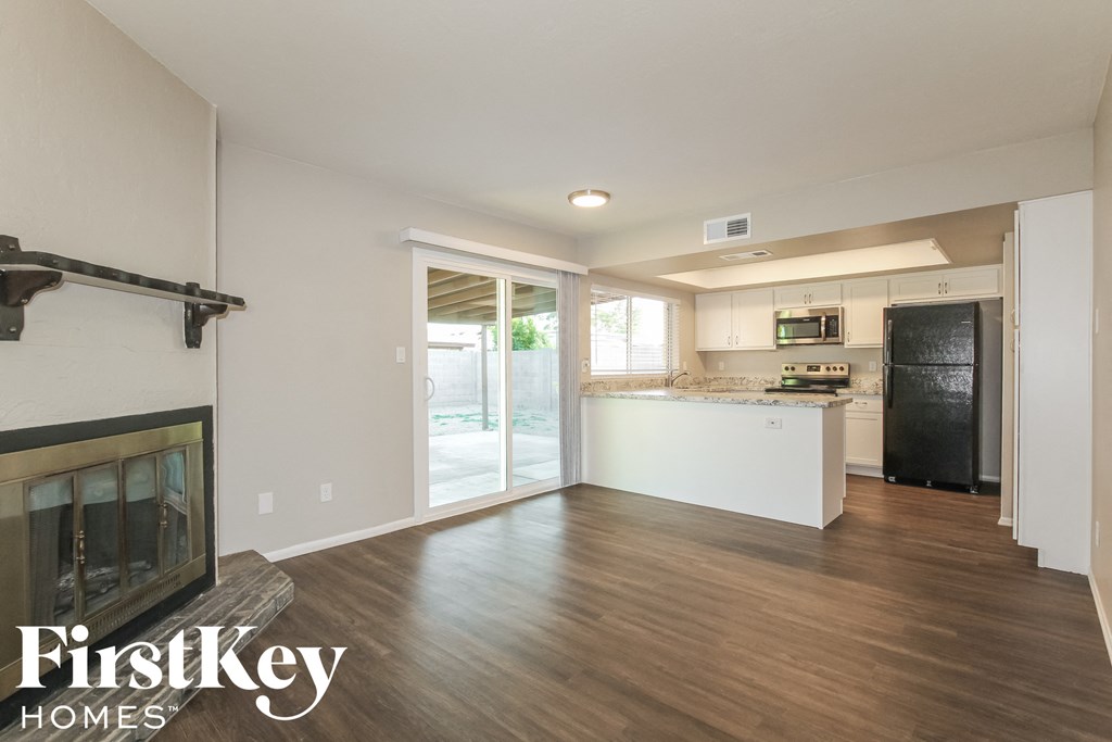 an empty living room with a fireplace and a kitchen