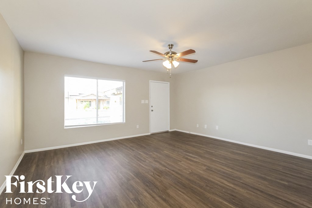 the spacious living room with wood flooring and a ceiling fan
