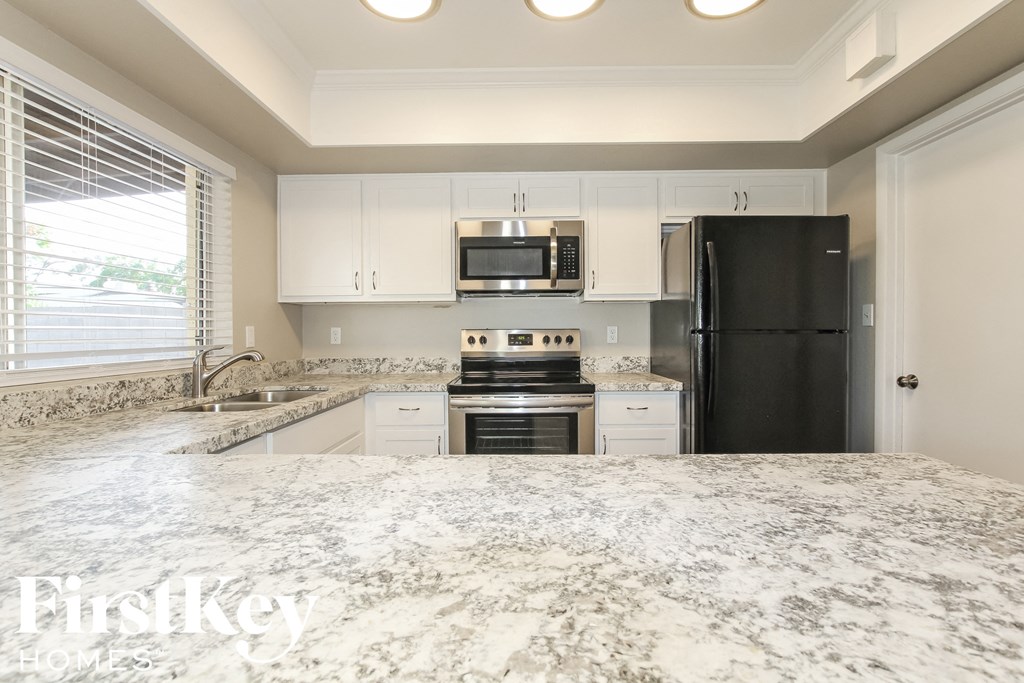 a kitchen with white cabinets and a marble counter top