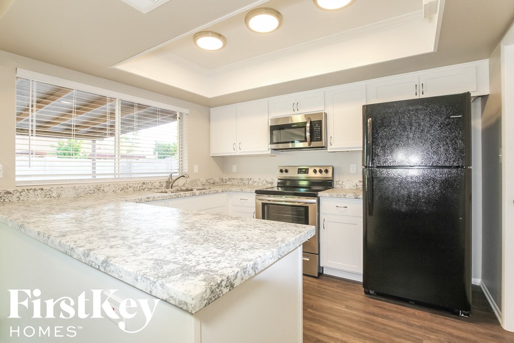 a kitchen with white cabinets and a marble counter top