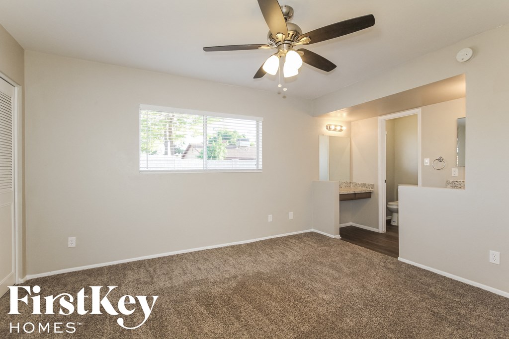 the spacious living room with ceiling fan and carpeted flooring