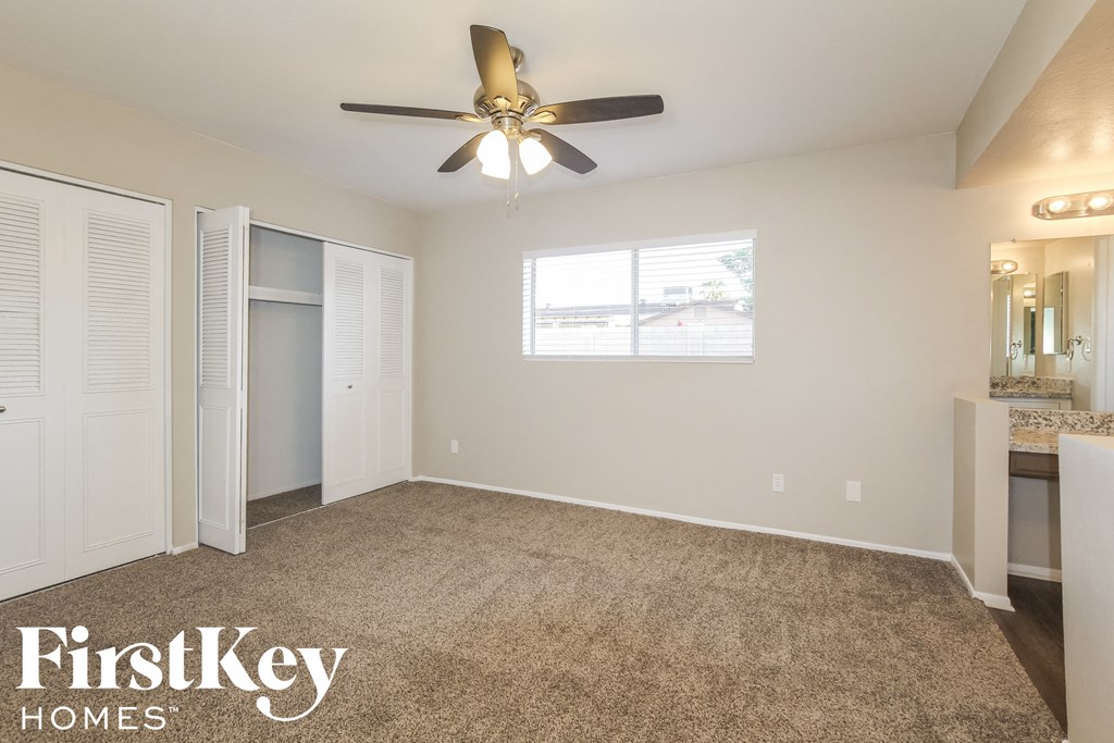 an empty living room with a ceiling fan and a closet
