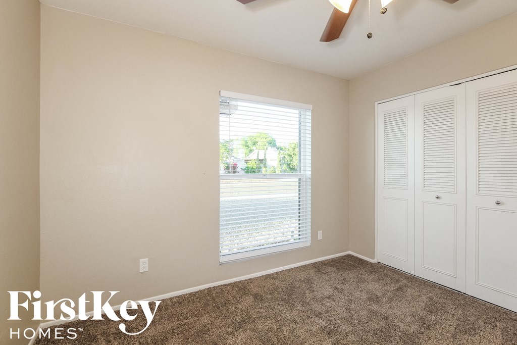 a bedroom with carpet and a window and white closets