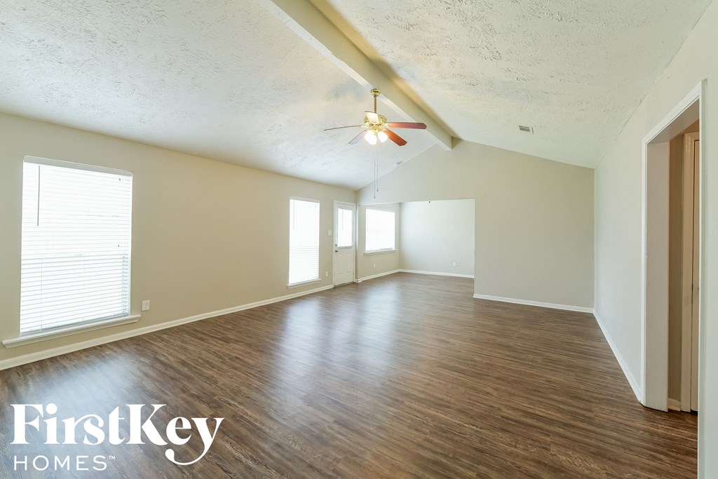 an empty living room with wood floors and a ceiling fan
