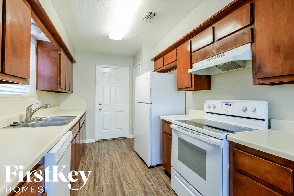 a kitchen with white appliances and wooden cabinets and a white refrigerator