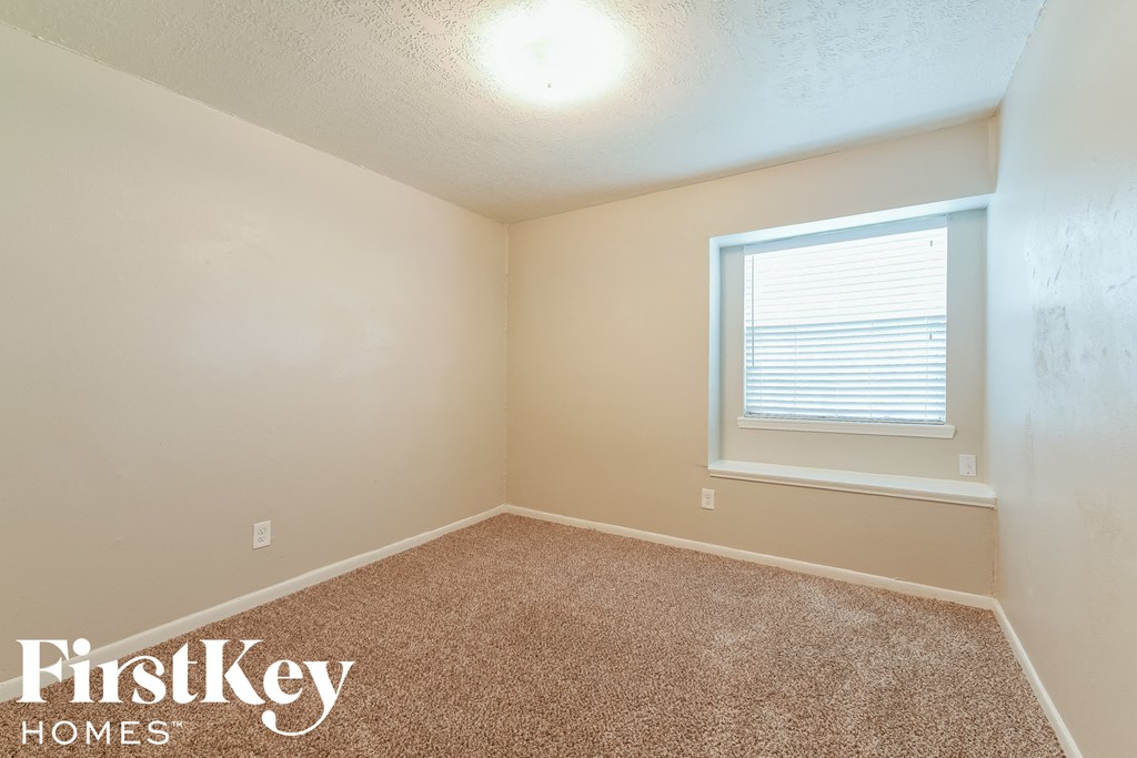 the bedroom of a small house with carpet and a window