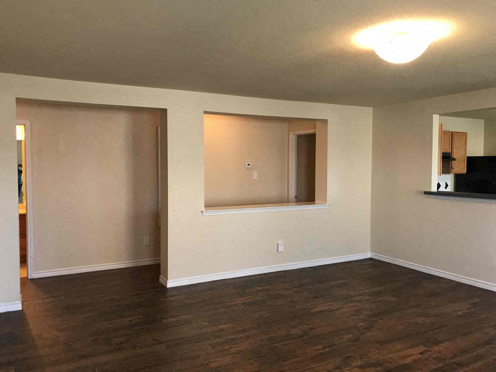 an empty living room with a hard wood floor and a window