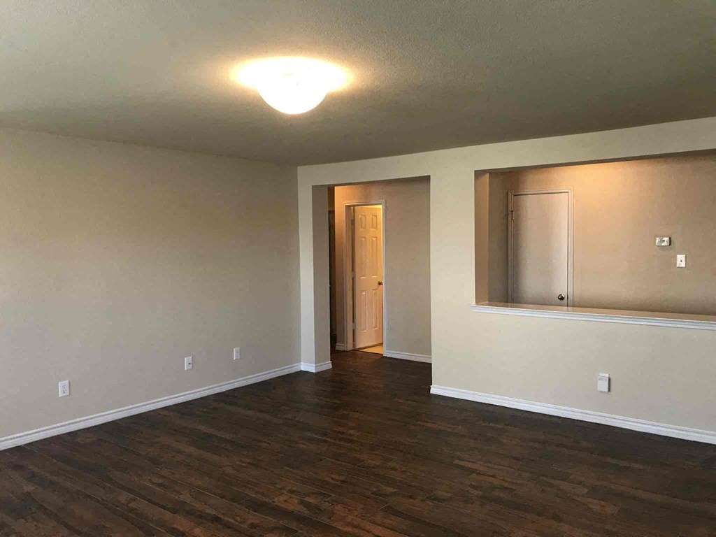 an empty living room with wood floors and a mirror