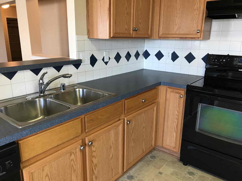 a kitchen with wooden cabinets and black counter tops and a sink