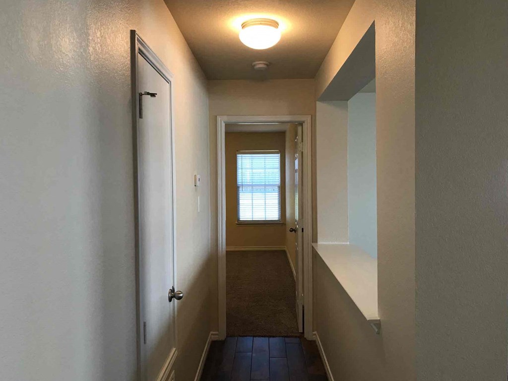 a hallway with a door and a window on the end of it