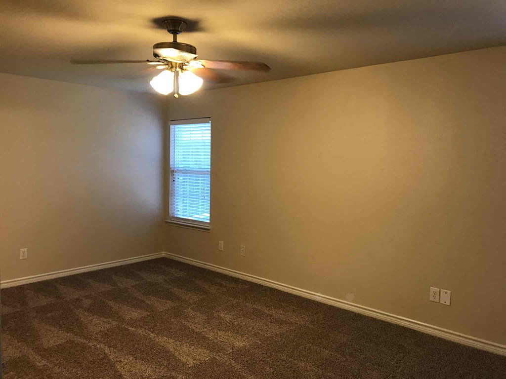 an empty living room with a ceiling fan and a window