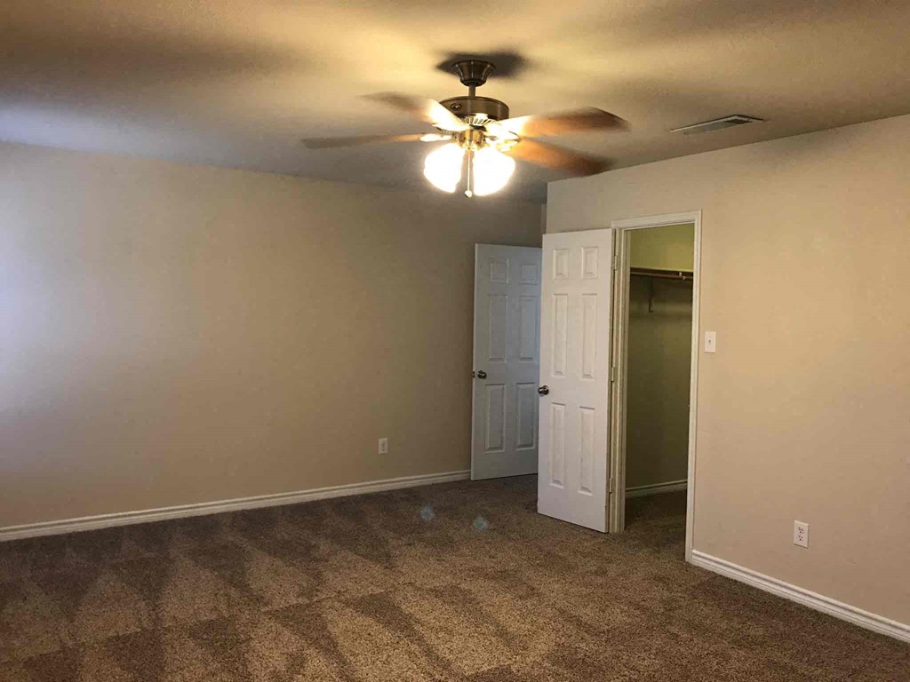 a empty room with a ceiling fan and a closet