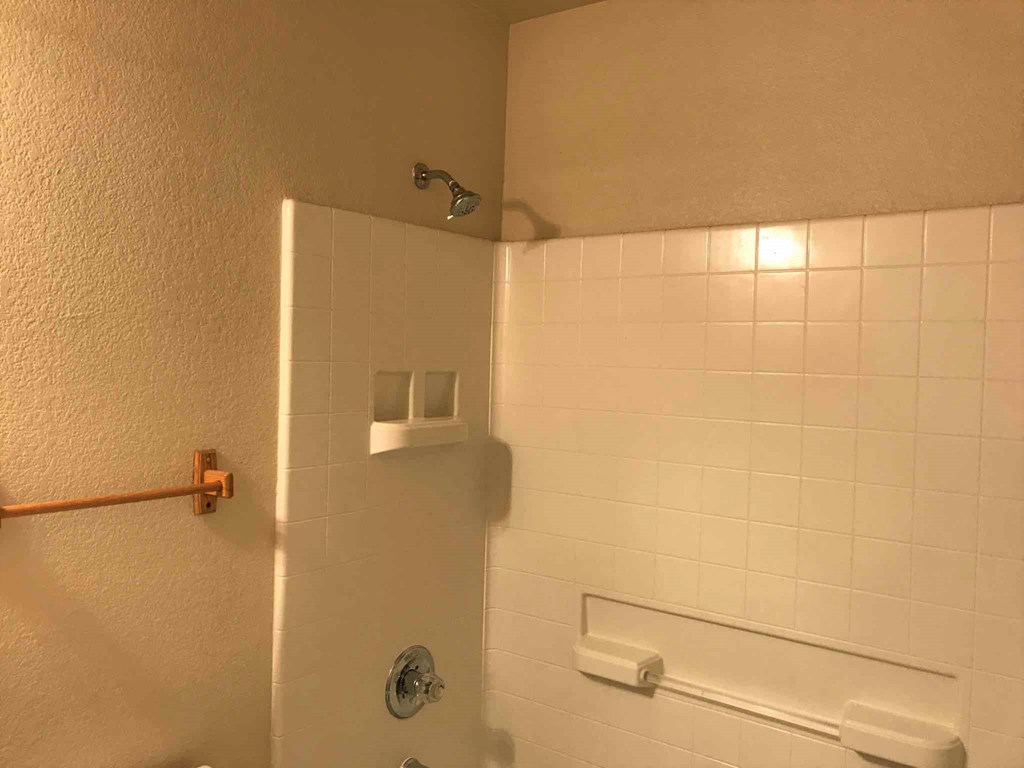 a bathroom with a toilet and a white tiled wall