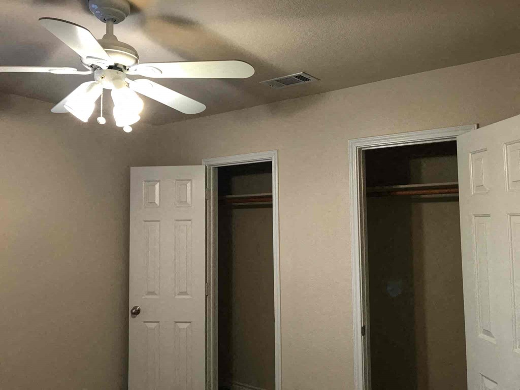 a room with a ceiling fan and a closet and a mirror