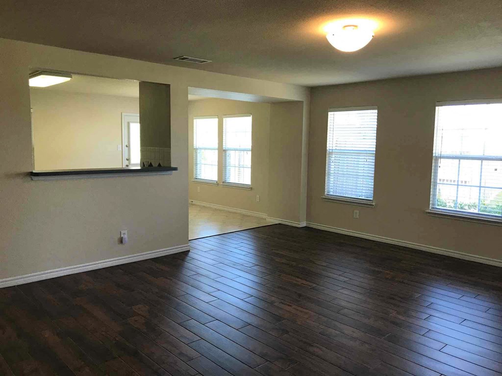 an empty living room with hard wood floors and a window