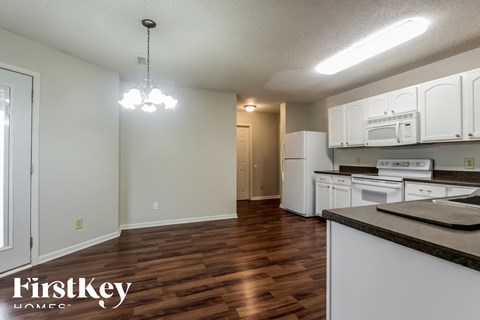 A kitchen with white cabinets and a wooden floor.