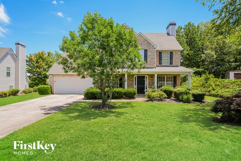 a home with a lawn and a tree in front of it