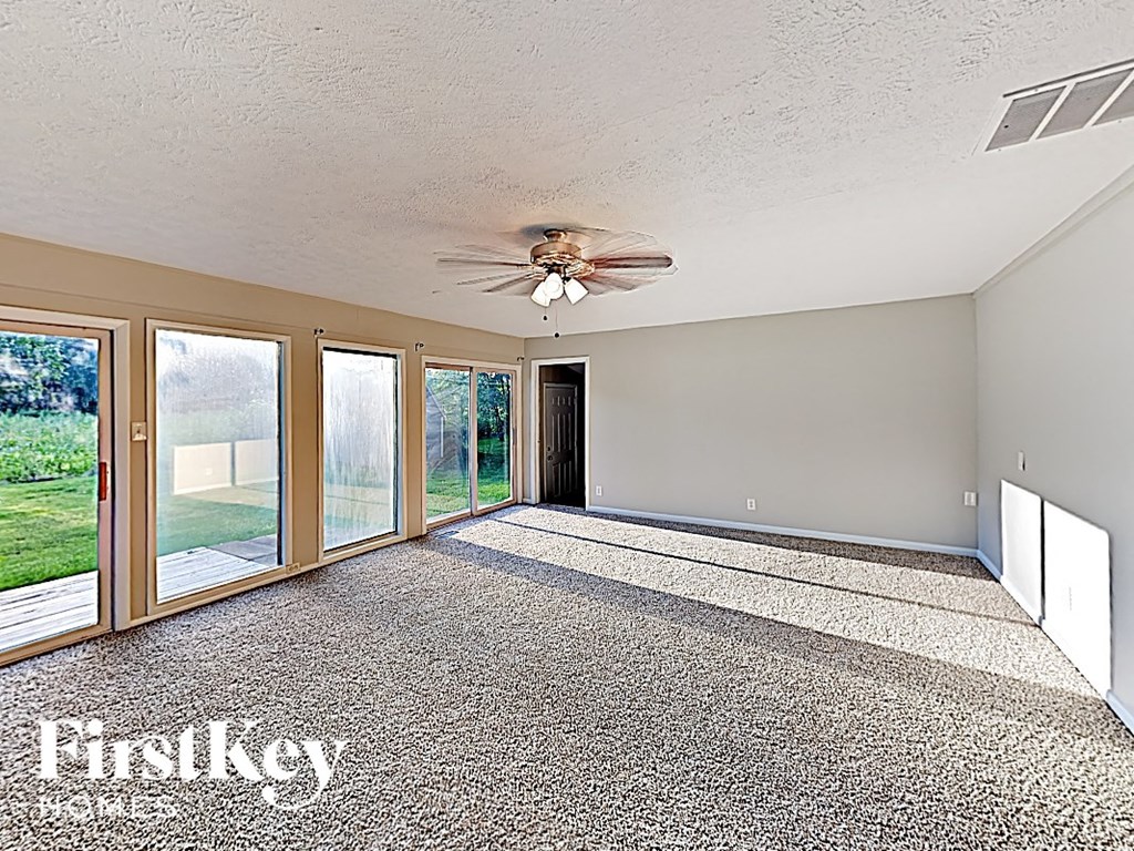 an empty living room with a ceiling fan and sliding glass doors