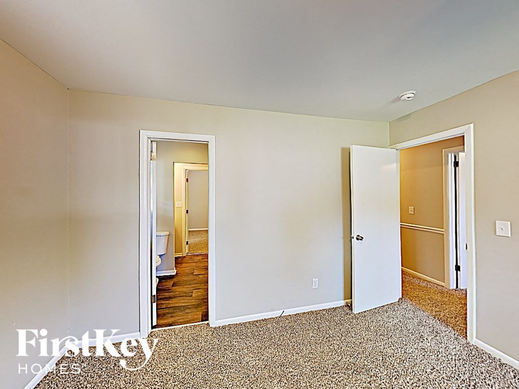 a bedroom with two doors and a hallway to a bathroom and a closet
