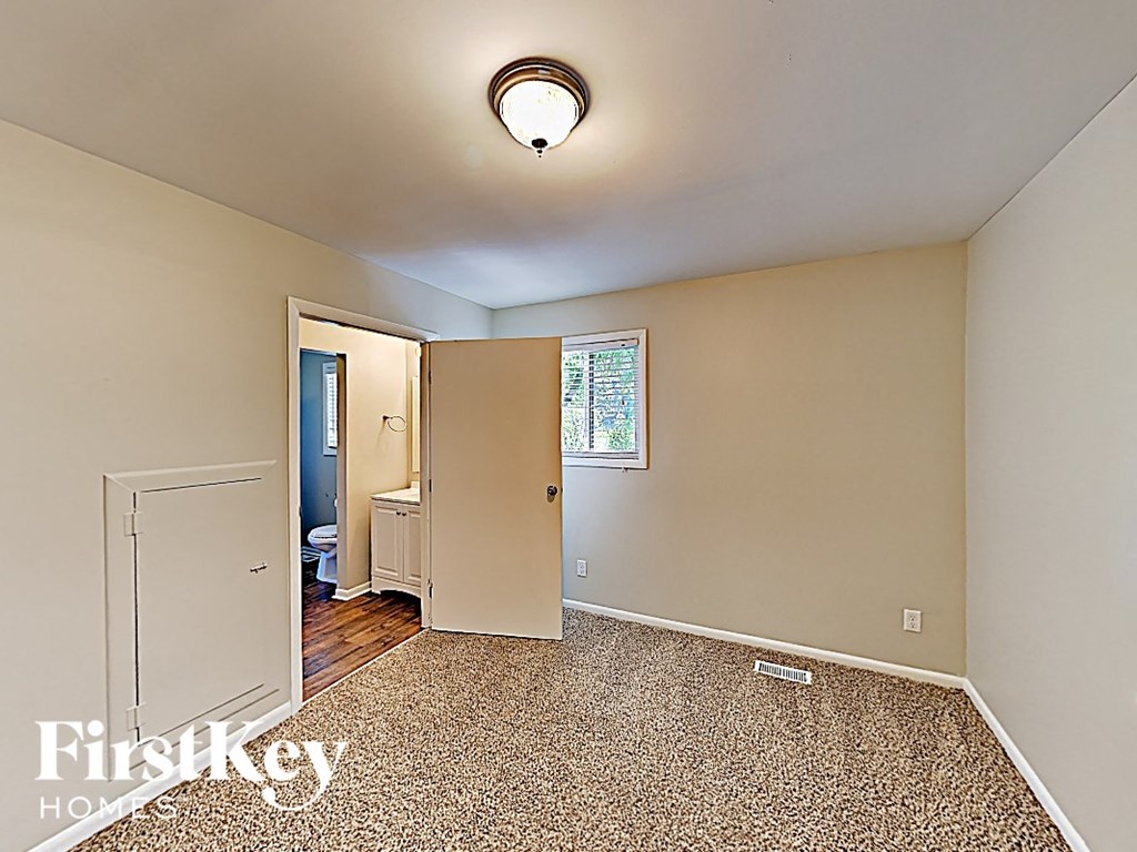 an empty bedroom with an open door to the bathroom