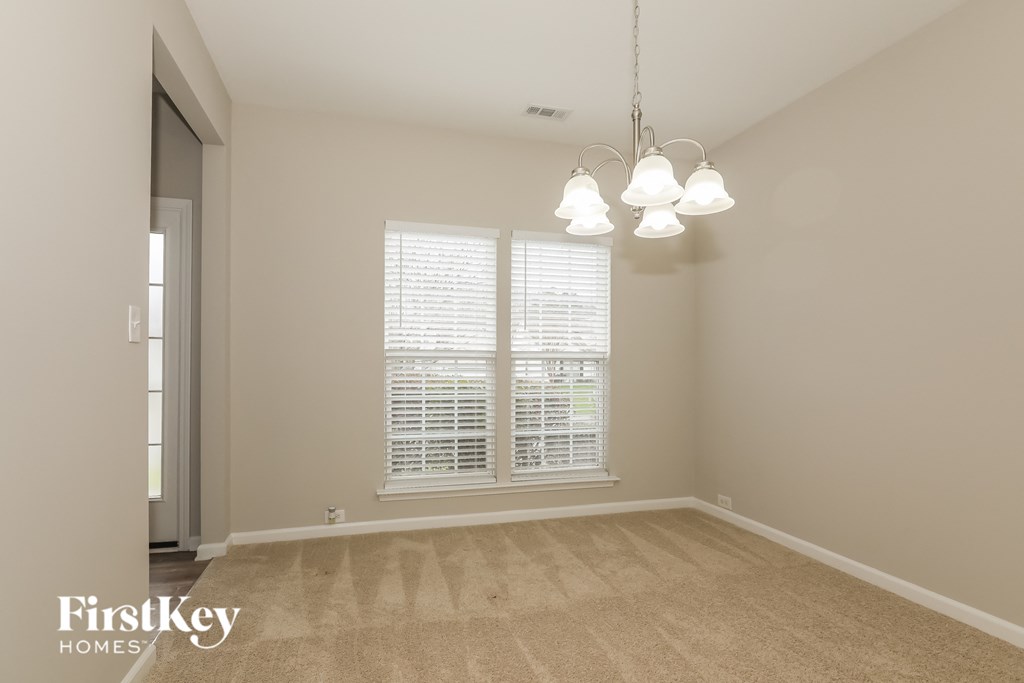 A room with a carpeted floor and a window with blinds.