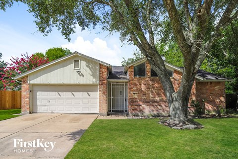 a brick house with a garage and a tree
