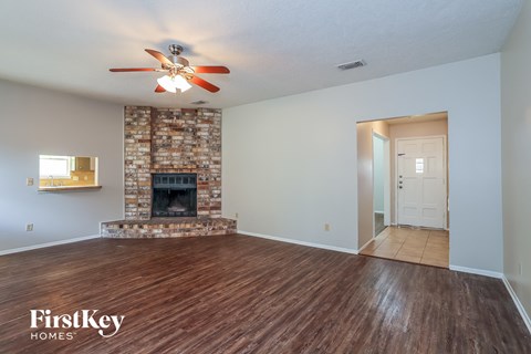 an empty living room with a fireplace and a ceiling fan