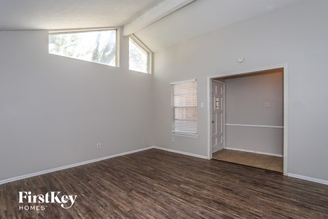 the living room of an apartment with a wood floor and a door to a closet