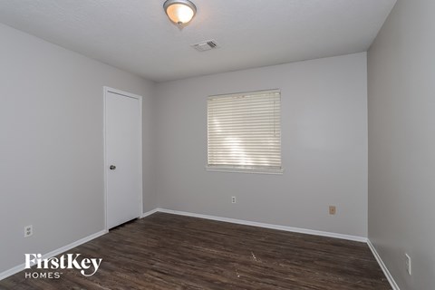 the living room of an empty house with wood flooring and a window