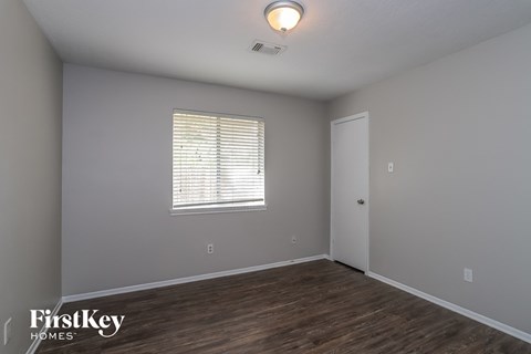 the spacious living room with wood flooring and a window