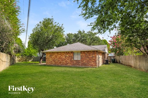a small brick house in the middle of a grassy yard