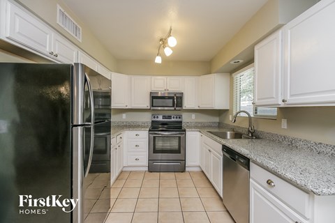 a kitchen with white cabinets and granite counter tops and black appliances
