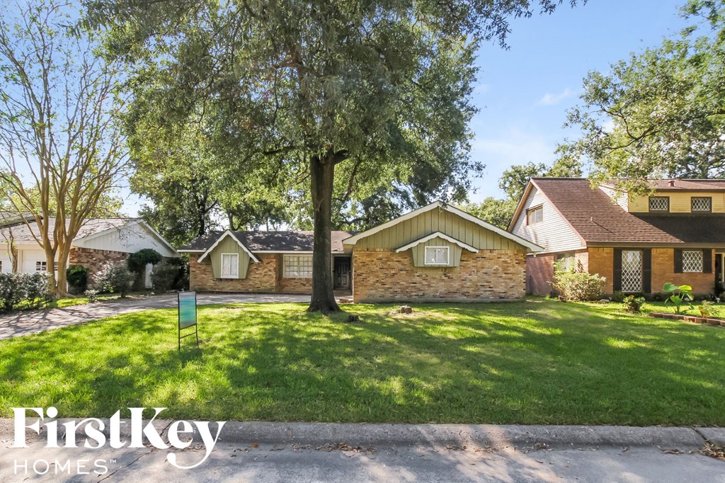the front of a house with a lawn and a tree