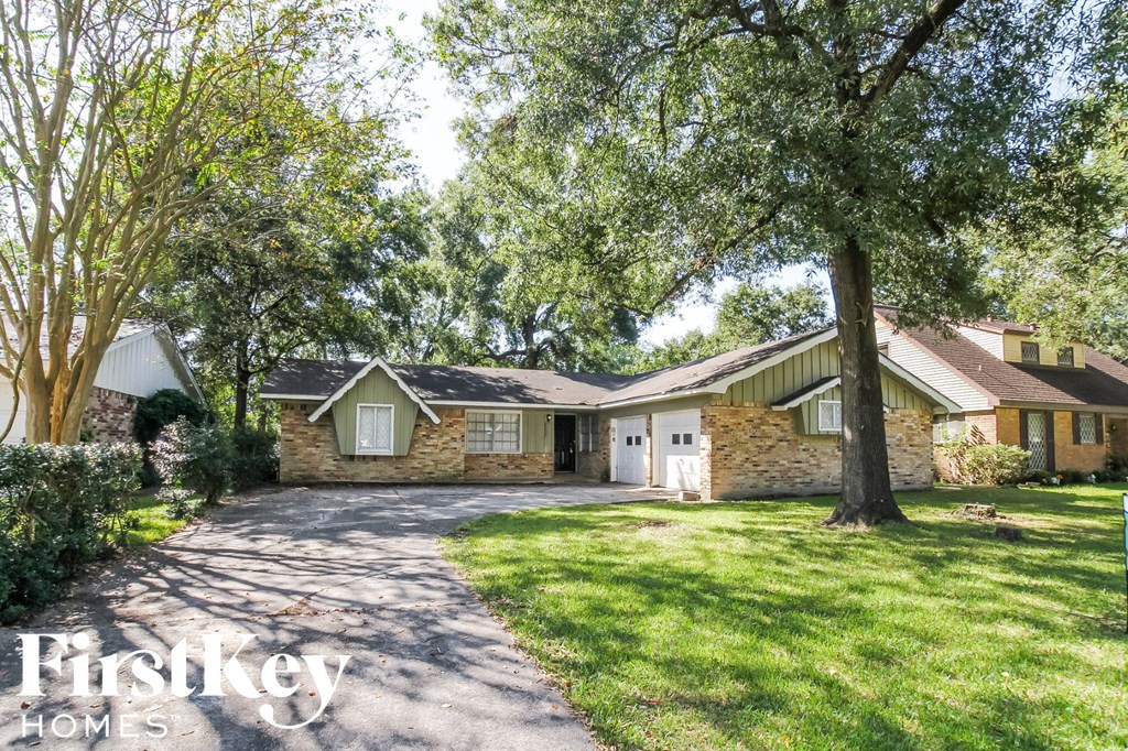 the front of a house with a driveway and a tree