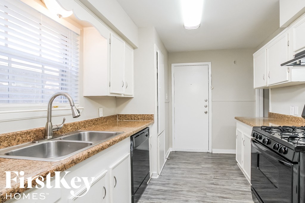 a kitchen with white cabinets and granite counter tops and a sink