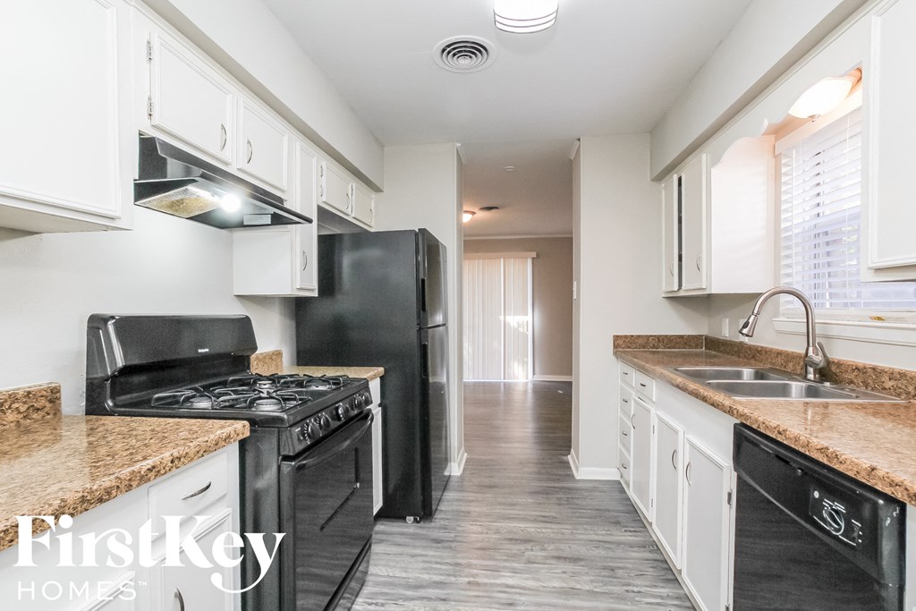 a kitchen with white cabinets and black appliances and a black refrigerator
