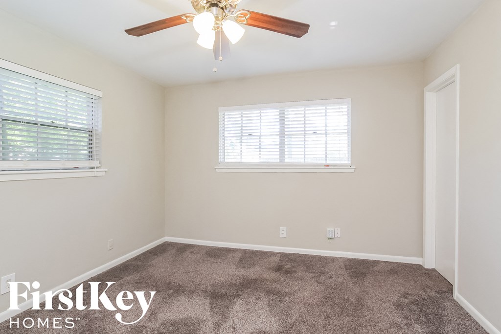 a bedroom with carpet and a ceiling fan and two windows