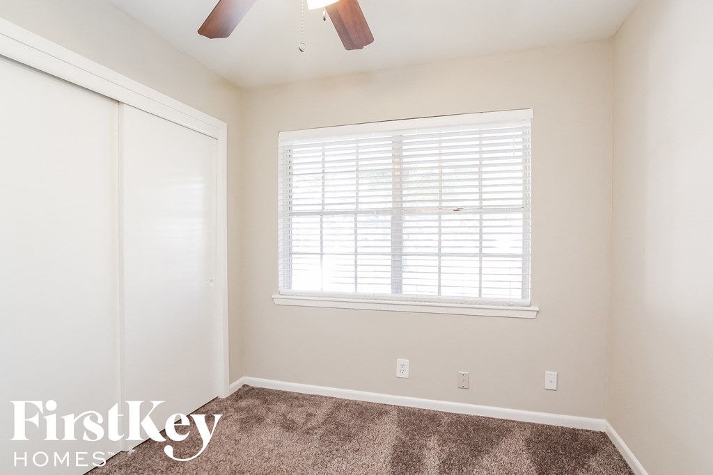 a bedroom with a window and a closet and a ceiling fan