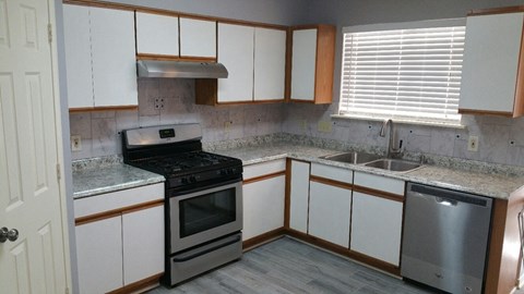 A kitchen with a stove, sink, and cabinets.
