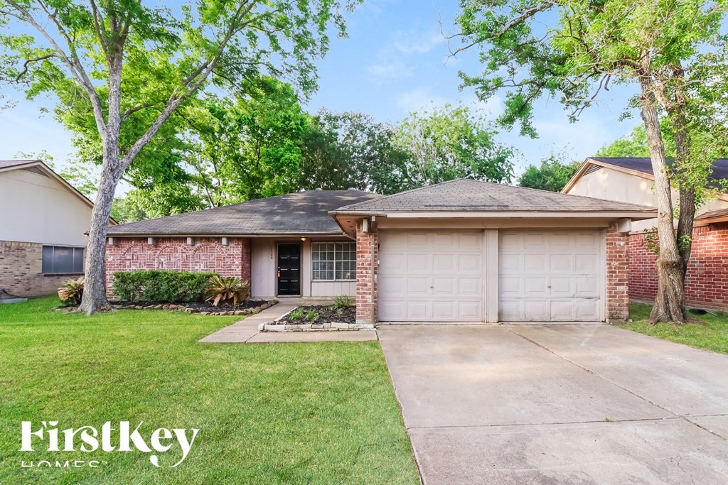 A brick house with a white garage door is for sale.
