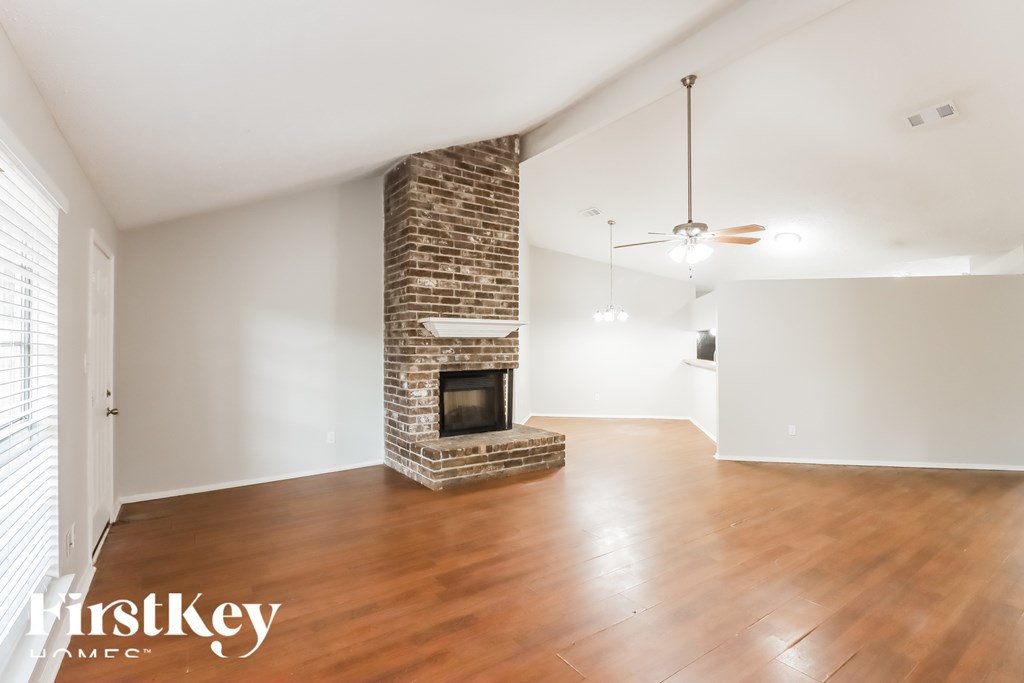 A room with a stone fireplace and wooden floors.