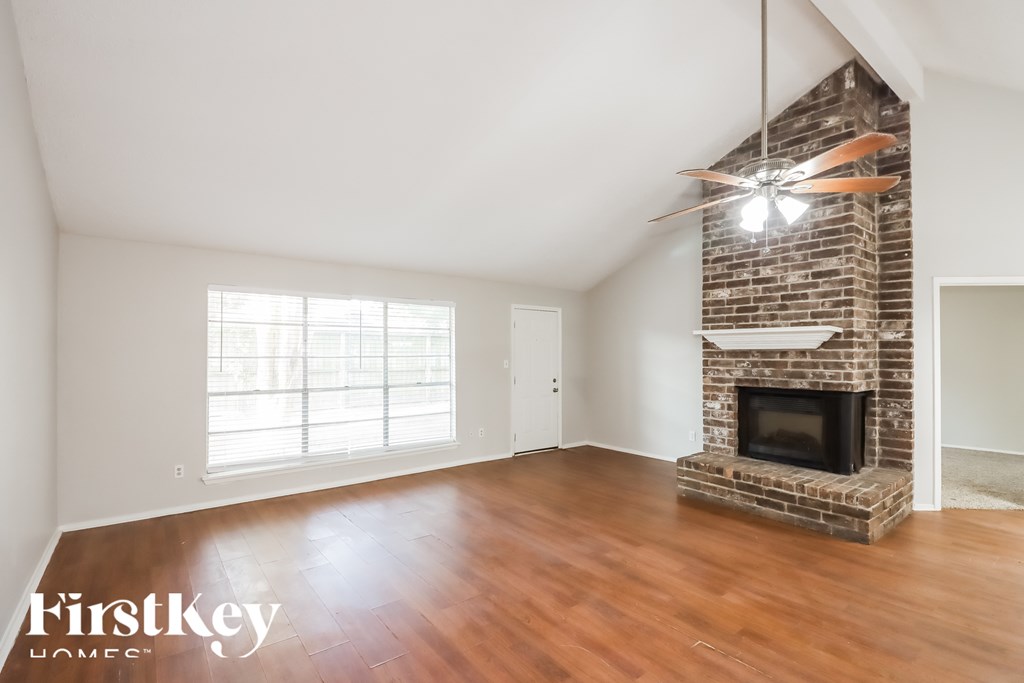 A room with a brick fireplace and a ceiling fan.