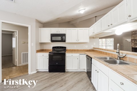 A kitchen with white cabinets and a black oven.