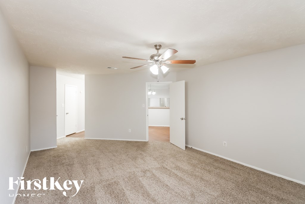 A spacious room with a ceiling fan and carpeted floor.