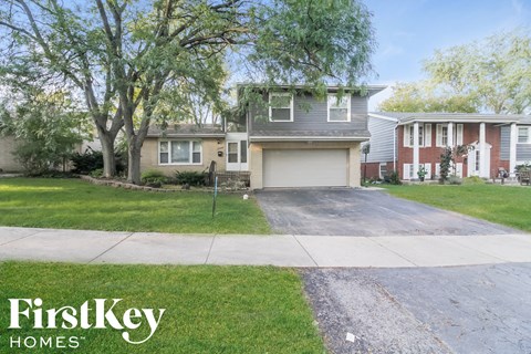 a house with a driveway and trees in front of it