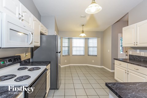 A kitchen with a black counter top and white cabinets.