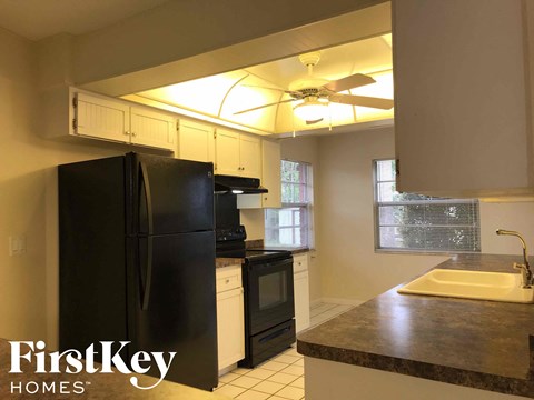 A kitchen with a black fridge and a black stove top oven.